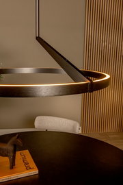 Moderne runde LED-Pendelleuchte in dunkler Metalloptik mit warmweiß leuchtendem Ring über einem Esstisch, perspektivisch in seitlicher Nahaufnahme von unten