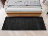 Schwarzer Hochflor-Teppich vor einem Bett aus Holz, Vogelperspektive