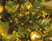 Nahaufnahme eines Weihnachtsbaums mit LED-Clusterbeleuchtung und goldener Kugel