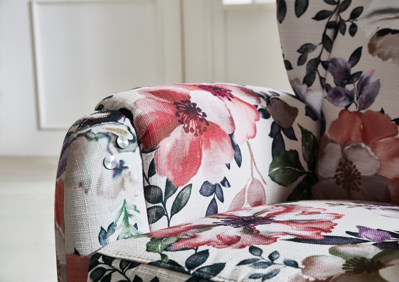 Nahaufnahme eines Cantus Fernsehsessels FRIESLAND mit floralem Muster in Rot- und Grüntönen, seitliche Perspektive.