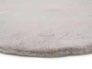 Nahaufnahme eines weichen, hellgrauen Fellteppichs mit flauschiger Textur.