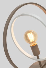 Close-up vanuit licht vooraanzicht van een moderne tafellamp met elegante metalen ringen en een sfeervol brandende filamentlamp