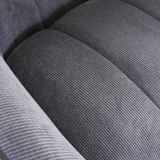 Nahaufnahme eines grauen, strukturierten Stoffes eines Armlehnstuhls, von oben betrachtet.