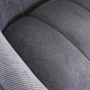 Nahaufnahme eines grauen, strukturierten Stoffes eines Armlehnstuhls, von oben betrachtet.