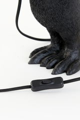 Nahaufnahme der Tischleuchte mit einem schwarzen Kabel und Schalter, sowie einem dekorativen Fuß in Tierform.
