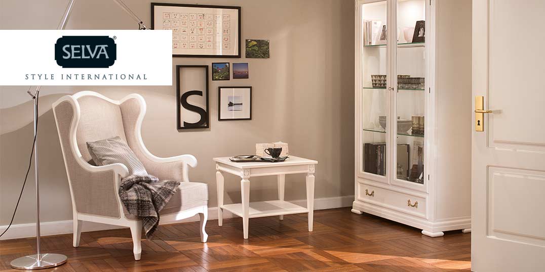 Eleganter Raum mit weißen Ohrensessel, Tisch, Vitrine der Marke Selva.