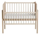 Anstellbett aus Holz in heller Farbe, frontal fotografiert, mit Gitterstäben und einer weißen Matratze.