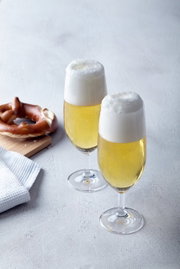 Zwei gefüllte Biergläser Daily mit Schaumkrone, von schräg oben fotografiert, neben einer Brezel auf einem Holzbrett.