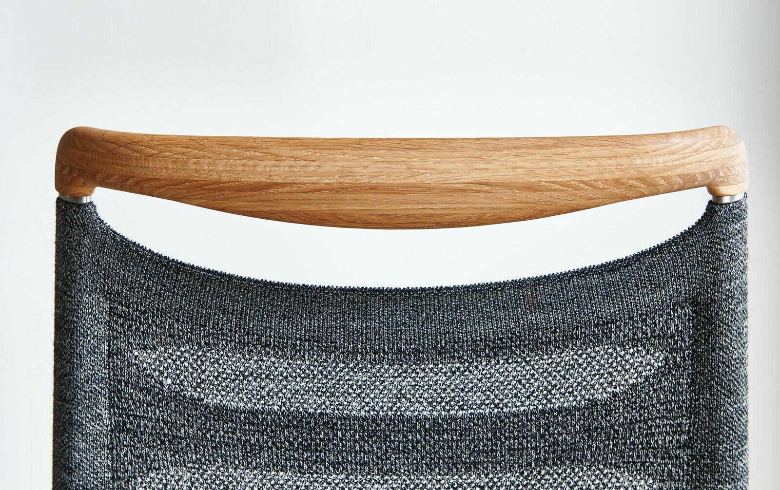 Rückansicht eines Freischwinger-Stuhls mit Holzlehne und grauem Stoffbezug