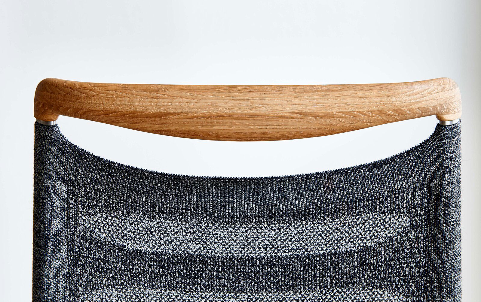 Rückansicht eines Freischwinger-Stuhls mit Holzlehne und grauem Stoffbezug