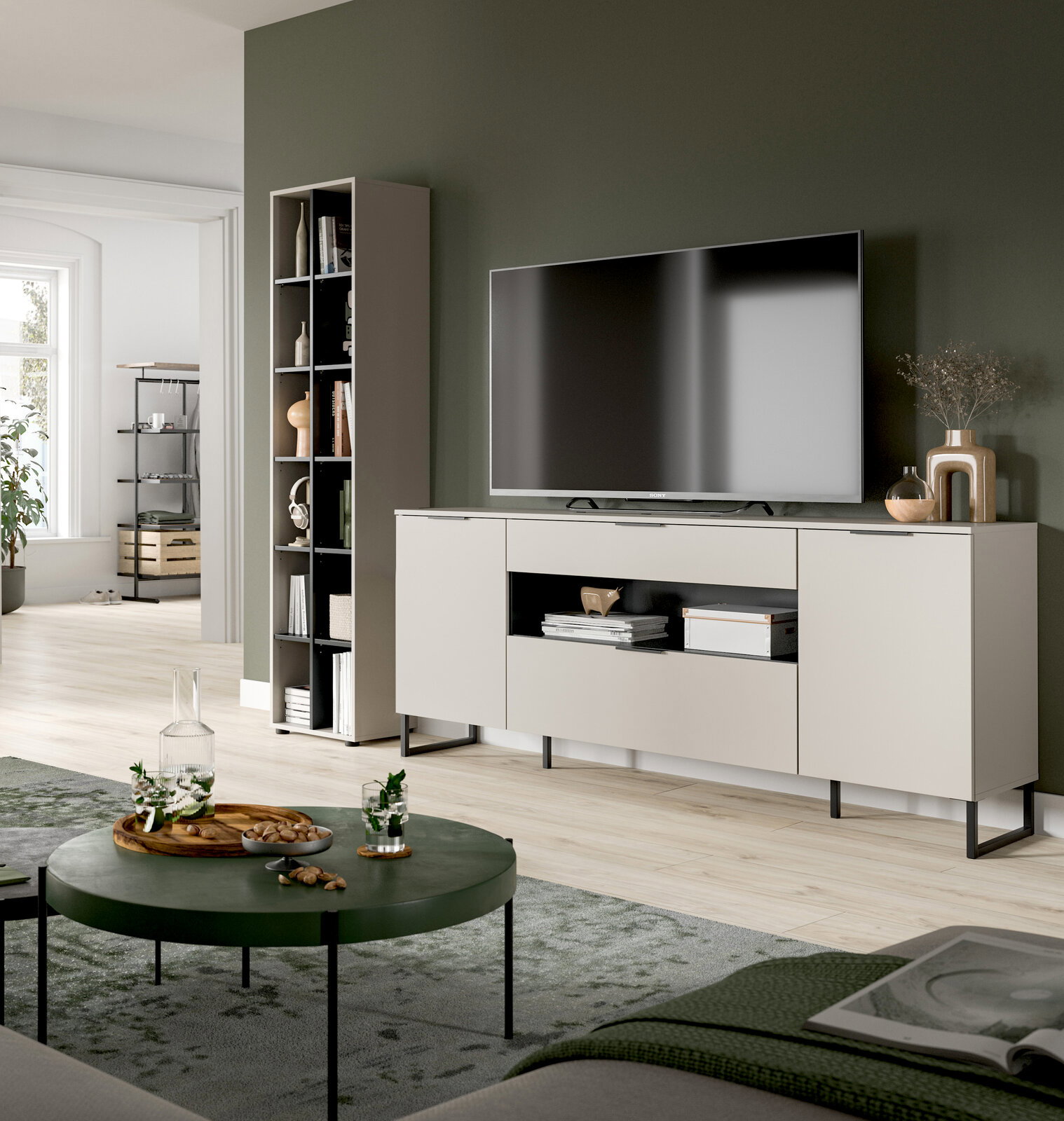 Modernes Wohnzimmer mit beigem TV-Lowboard auf schwarzen Metallfüßen und großem Fernseher, daneben hohes Regal; Aufnahme aus leicht schräger Frontperspektive.