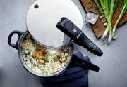 Draufsicht auf einen Schnellkochtopf mit Reis und Pilzen, umgeben von Frühlingszwiebeln und Salz.