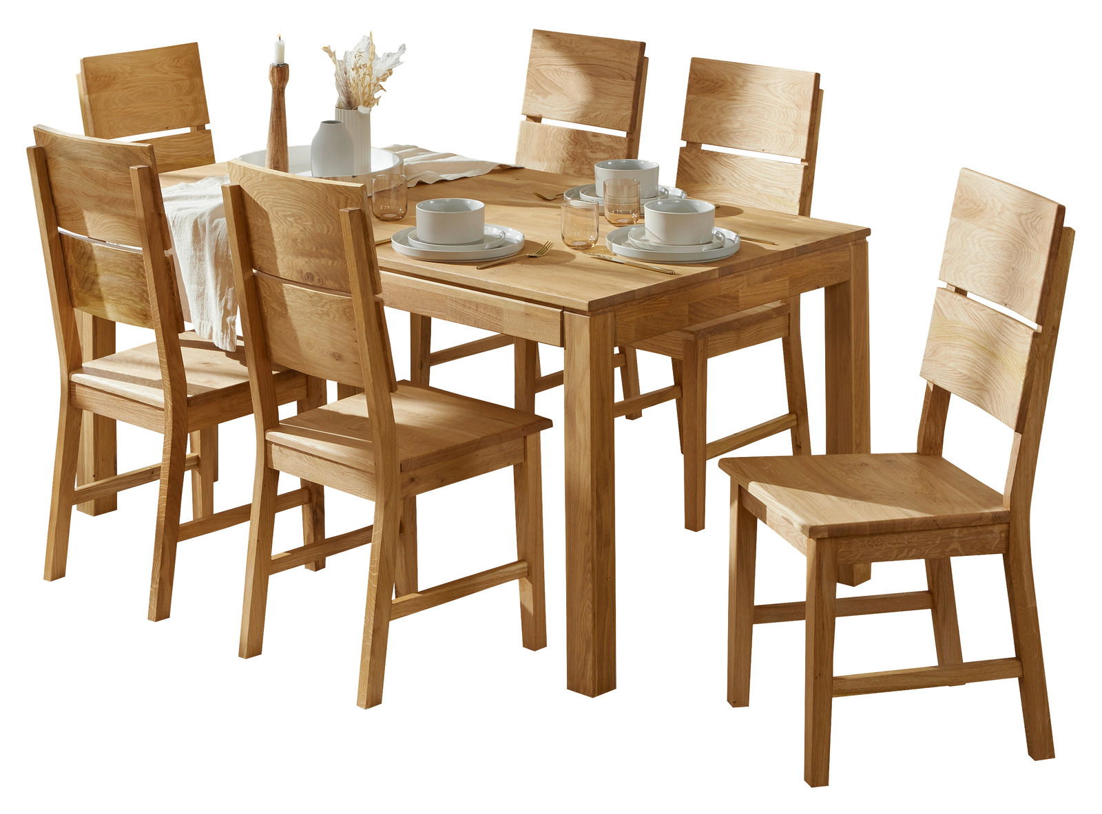 Holzesstisch mit sechs passenden Stühlen, gedeckt mit Geschirr und Dekoration, aus schräger Perspektive fotografiert.