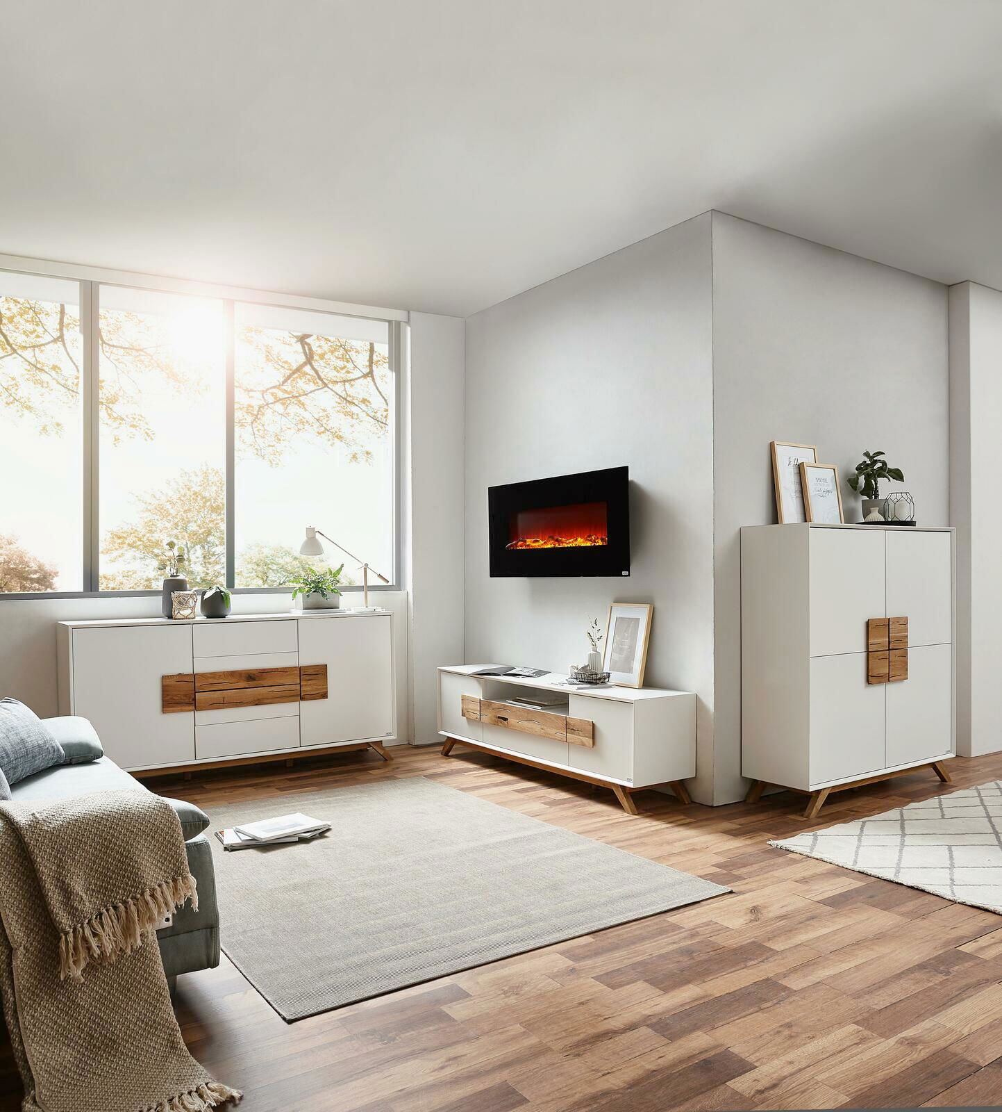 Modernes Wohnzimmer mit weißem Highboard, Sideboard und TV-Lowboard aus Holz und weißen Fronten, seitliche Perspektive