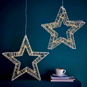 Zwei hängende LED-Sterne mit 960 LEDs, die in einem modernen Raum vor einer dunkelblauen Wand leuchten. Perspektive von vorne.