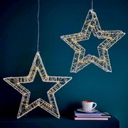 Zwei hängende LED-Sterne mit 960 LEDs, die in einem modernen Raum vor einer dunkelblauen Wand leuchten. Perspektive von vorne.