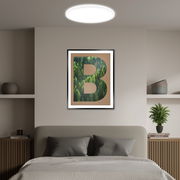 Rundes LED-Paneel an der Decke eines modern eingerichteten Schlafzimmers, von unten betrachtet.