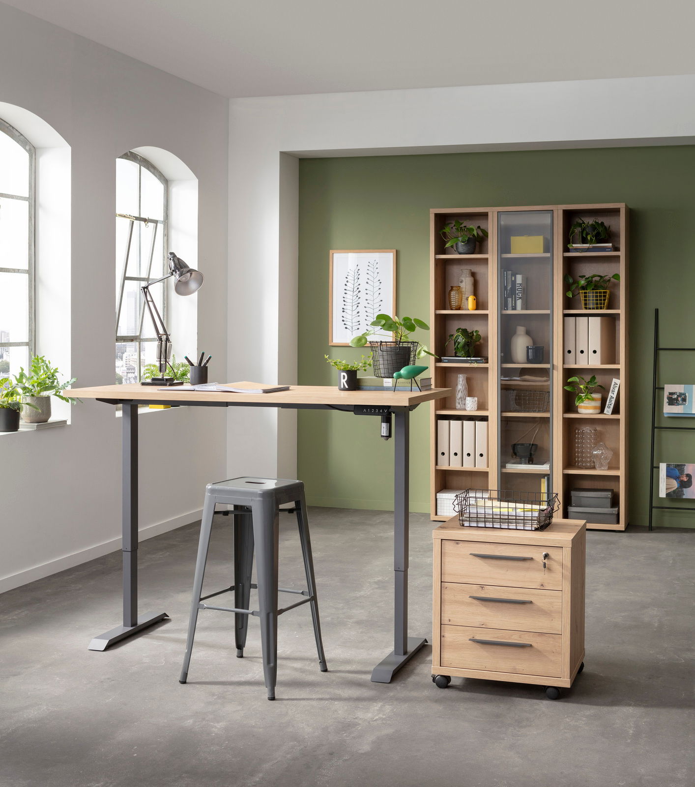 Elektrisch höhenverstellbarer Tisch mit Holzplatte und grauem Metallgestell, seitliche Perspektive, in modernem Büro mit Pflanzen und Regalen