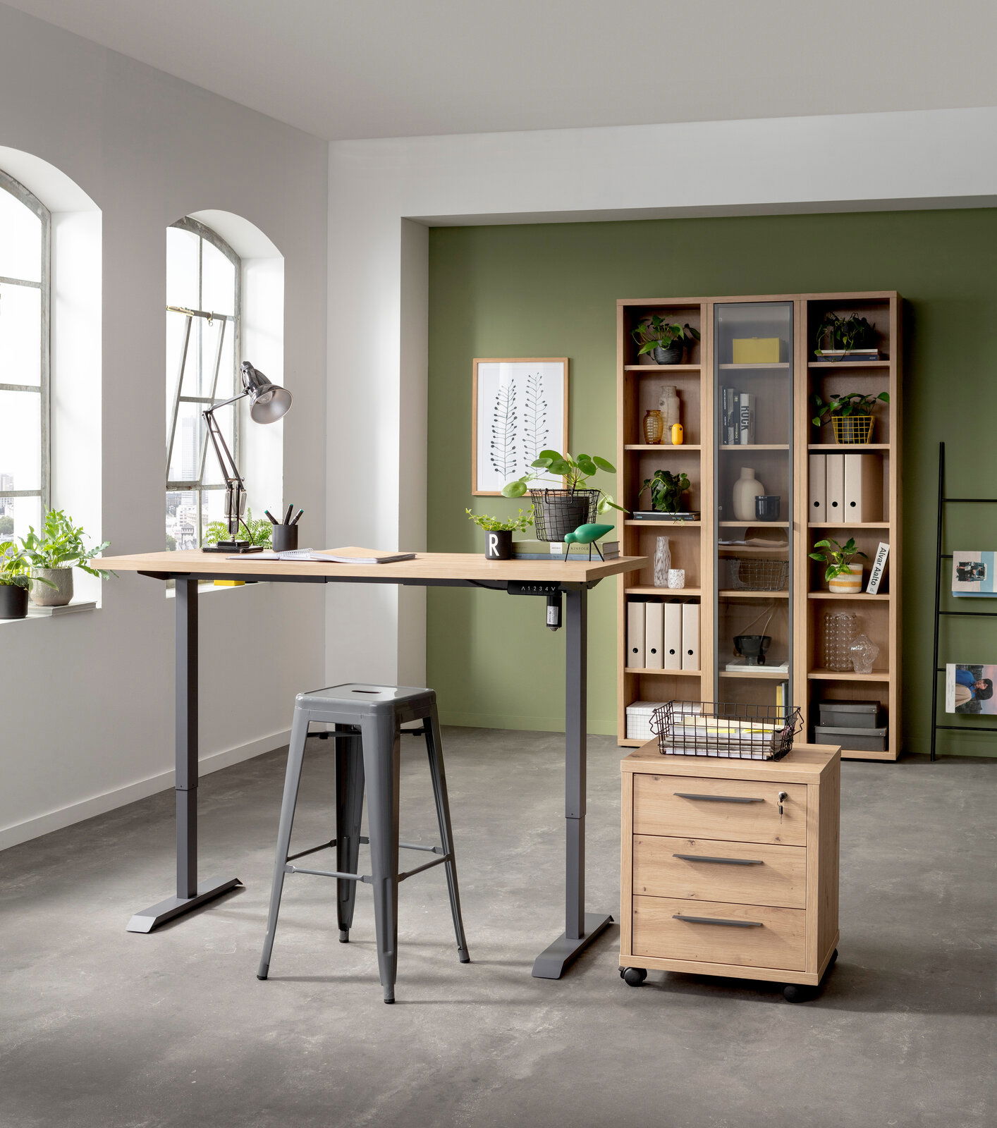 Elektrisch höhenverstellbarer Tisch mit Holzplatte und grauem Metallgestell, seitliche Perspektive, in modernem Büro mit Pflanzen und Regalen