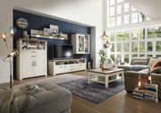 Wohnzimmer mit moderner Wohnwand, bestehend aus Highboard, Lowboard, Hängeelement und Wandboard, in heller Holzoptik. Perspektive von der Seite mit Blick auf die gesamte Einrichtung.