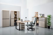 Moderne Büromöbel in einem hellen Raum, bestehend aus einem Schreibtisch mit Rollcontainer, mehreren Aktenschränken und einem ergonomischen Bürostuhl. Perspektive von vorne.