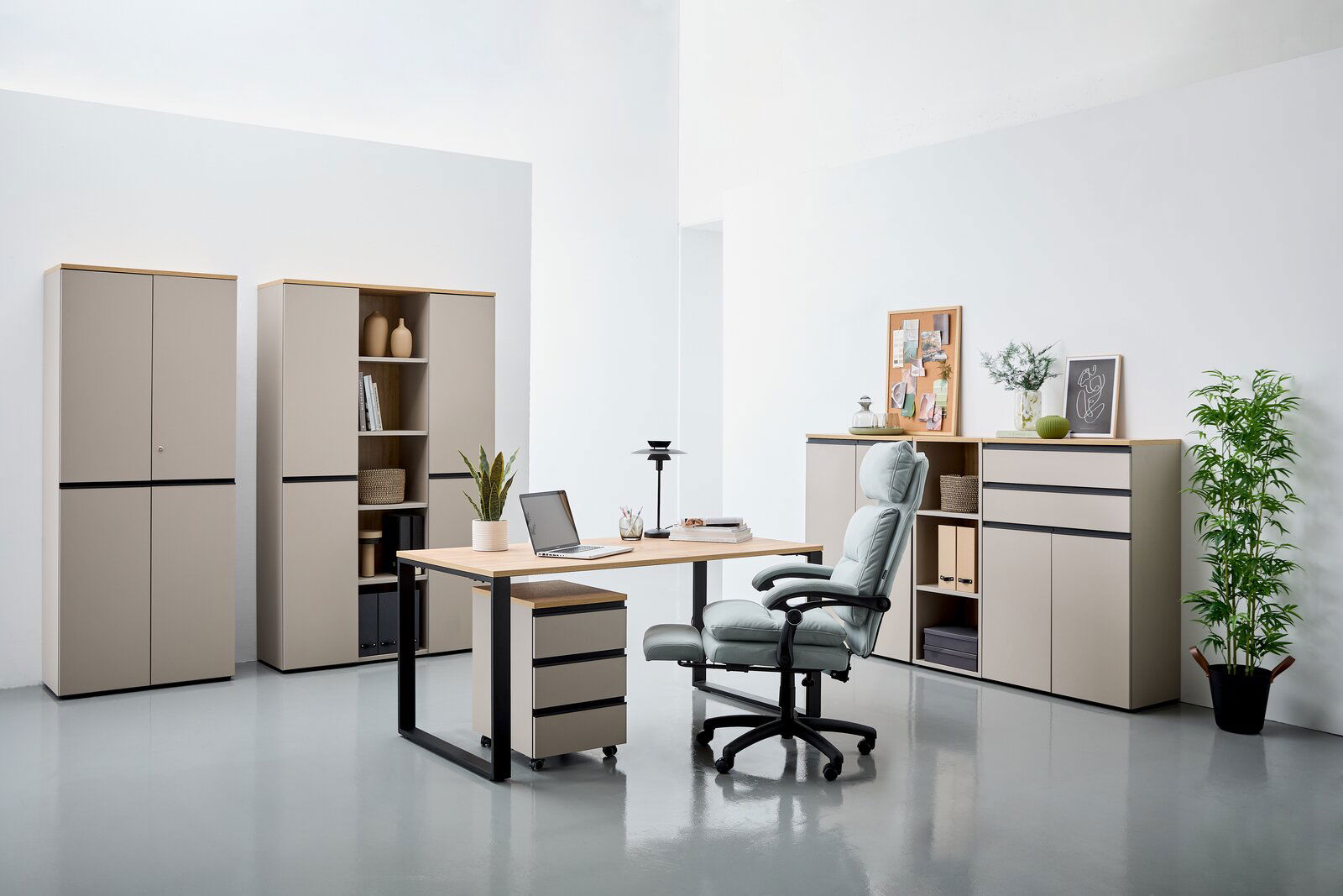 Moderne Büromöbel in einem hellen Raum, bestehend aus einem Schreibtisch mit Rollcontainer, mehreren Aktenschränken und einem ergonomischen Bürostuhl. Perspektive von vorne.