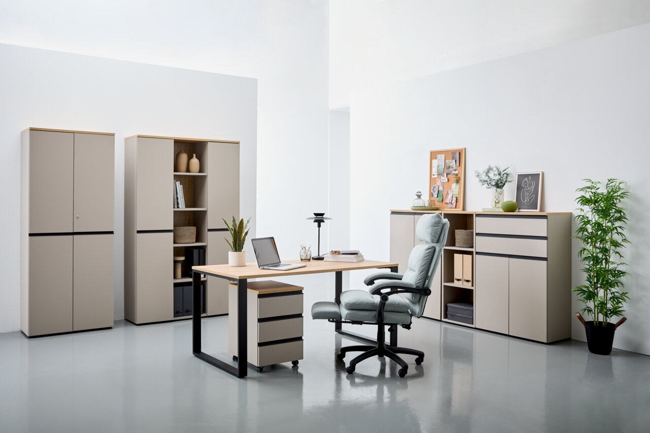 Novel Rollcontainer DELTONA Moderne Büromöbel in einem hellen Raum, bestehend aus einem Schreibtisch mit Rollcontainer, mehreren Aktenschränken und einem ergonomischen Bürostuhl. Perspektive von vorne.