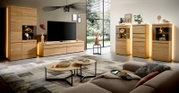 Modernes Wohnzimmermöbel-Set aus hellem Massivholz mit TV-Lowboard, Vitrinen, Highboard und beleuchteten Schränken, präsentiert in frontaler Weitwinkelansicht in einem stilvollen Wohnambiente.