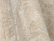 Nahaufnahme eines Designer-Teppichs mit beige-weißen Mustern, perspektivisch von der Seite aufgenommen.