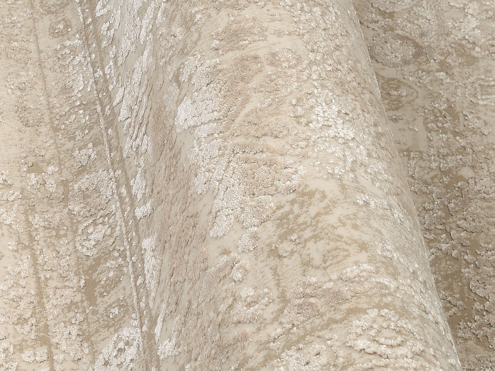 Nahaufnahme eines Designer-Teppichs mit beige-weißen Mustern, perspektivisch von der Seite aufgenommen.