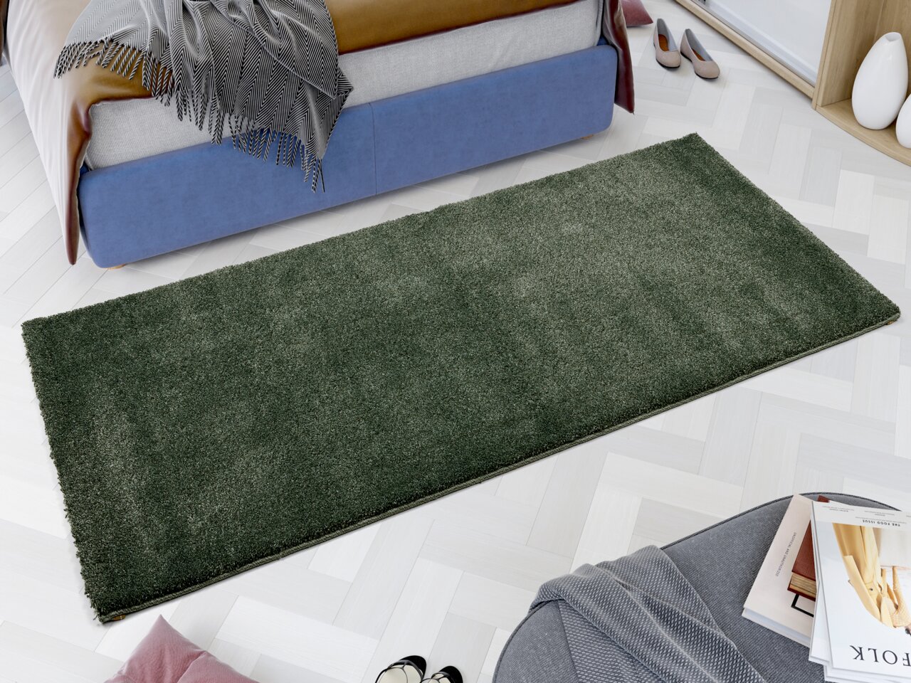 Grüner Uni-Teppich in rechteckiger Form, aus der Vogelperspektive in einem modernen Schlafzimmer mit hellem Parkettboden und blauer Bettumrandung fotografiert.