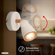 Schwenkbarer Wandstrahler mit zwei verstellbaren Spotköpfen in Weiß und Kupfer, warm leuchtend, in seitlicher Nahaufnahme aus leicht schräger Perspektive