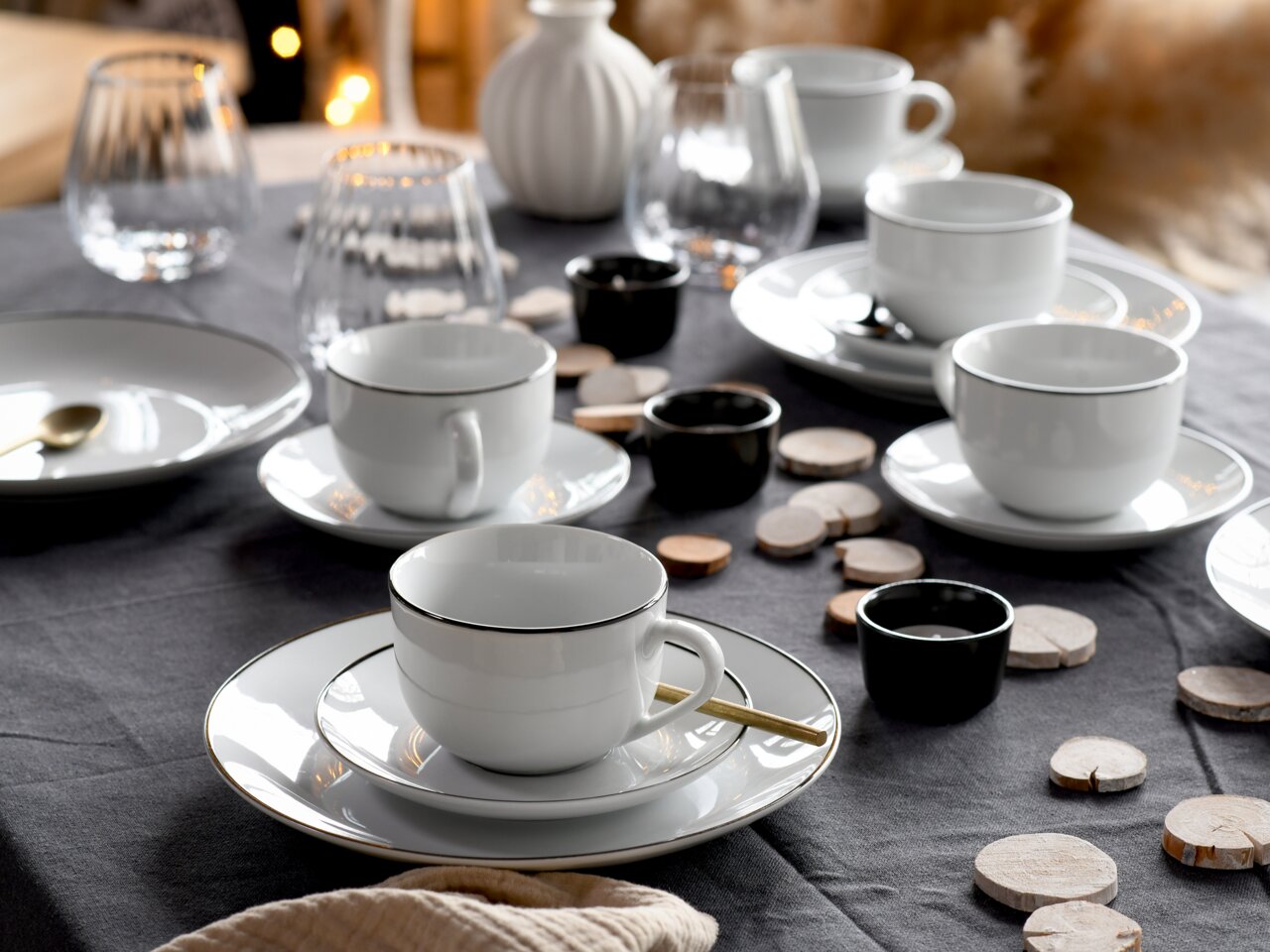 Elegantes Kaffeeservice Luna Black L, 18-teilig, auf einem gedeckten Tisch mit schwarzem Tischtuch, aus der Perspektive von schräg oben fotografiert.