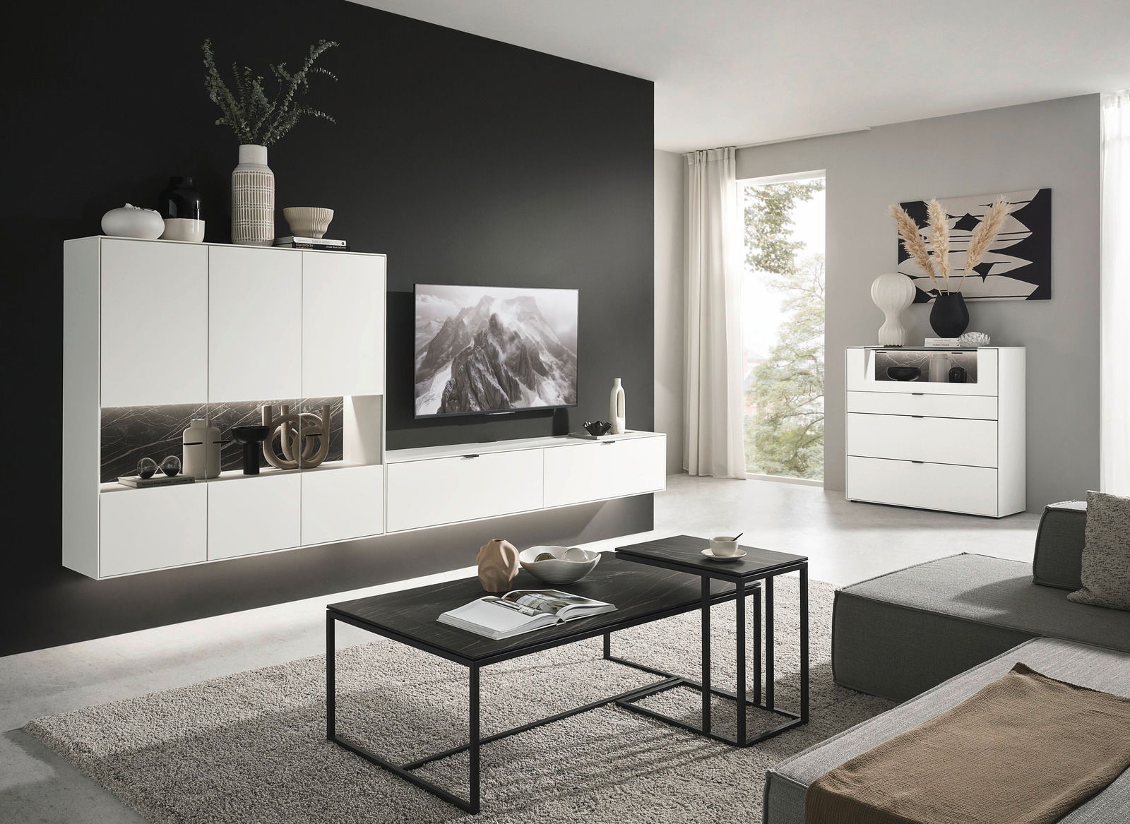 Moderne Wohnzimmer-Wandkombination in Weiß mit integriertem TV, dekorativen Vasen und Regalen, seitliche Perspektive.
