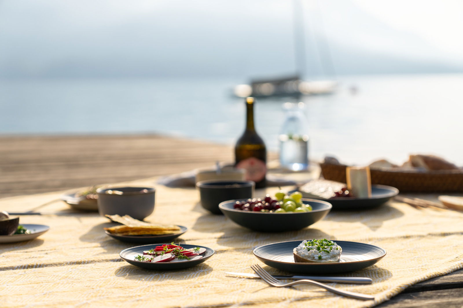 Thomas Suppenteller NATURE Suppenteller 23 cm auf einem gedeckten Tisch mit Blick auf einen See im Hintergrund