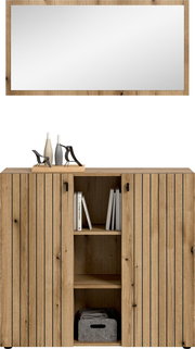 Frontansicht einer modernen Holz-Kommode/Sideboard in Eicheoptik mit zwei gerillten Türen, mittigem offenen Regal mit Büchern und Stoffbox sowie Deko auf der Oberseite vor weißem Hintergrund