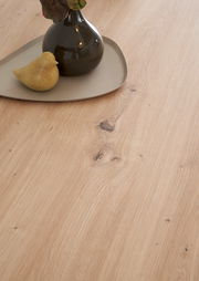 Nahaufnahme einer Kücheninsel mit Holzmaserung, dekoriert mit einer Vase und einem kleinen Vogel aus Keramik, von oben betrachtet.