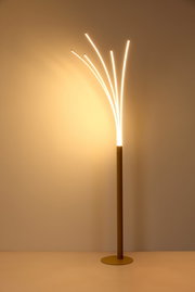 Moderne LED-Stehleuchte in Messing/Gold mit fünf gebogenen Lichtstäben, warmweiß leuchtend, freigestellt vor beigem Hintergrund; Perspektive: frontale Ansicht leicht von links.