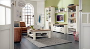 Wohnzimmer mit moderner Einrichtung, bestehend aus einem Couchtisch, einem Sideboard mit Fernseher und Regalen, in einer hellen und gemütlichen Atmosphäre. Perspektive von der Tür aus.