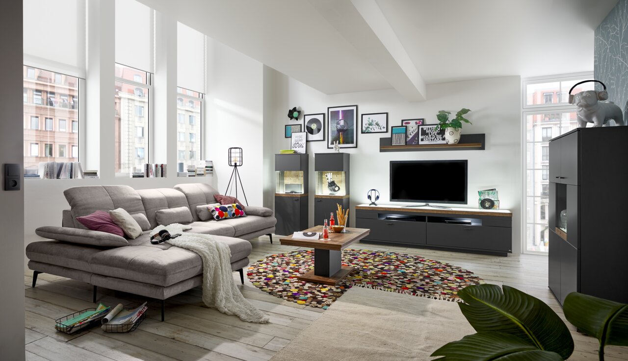 Modernes Wohnzimmer mit grauem Sofa, Couchtisch und TV-Lowboard in einer hellen, stilvollen Umgebung. Perspektive von der Seite.