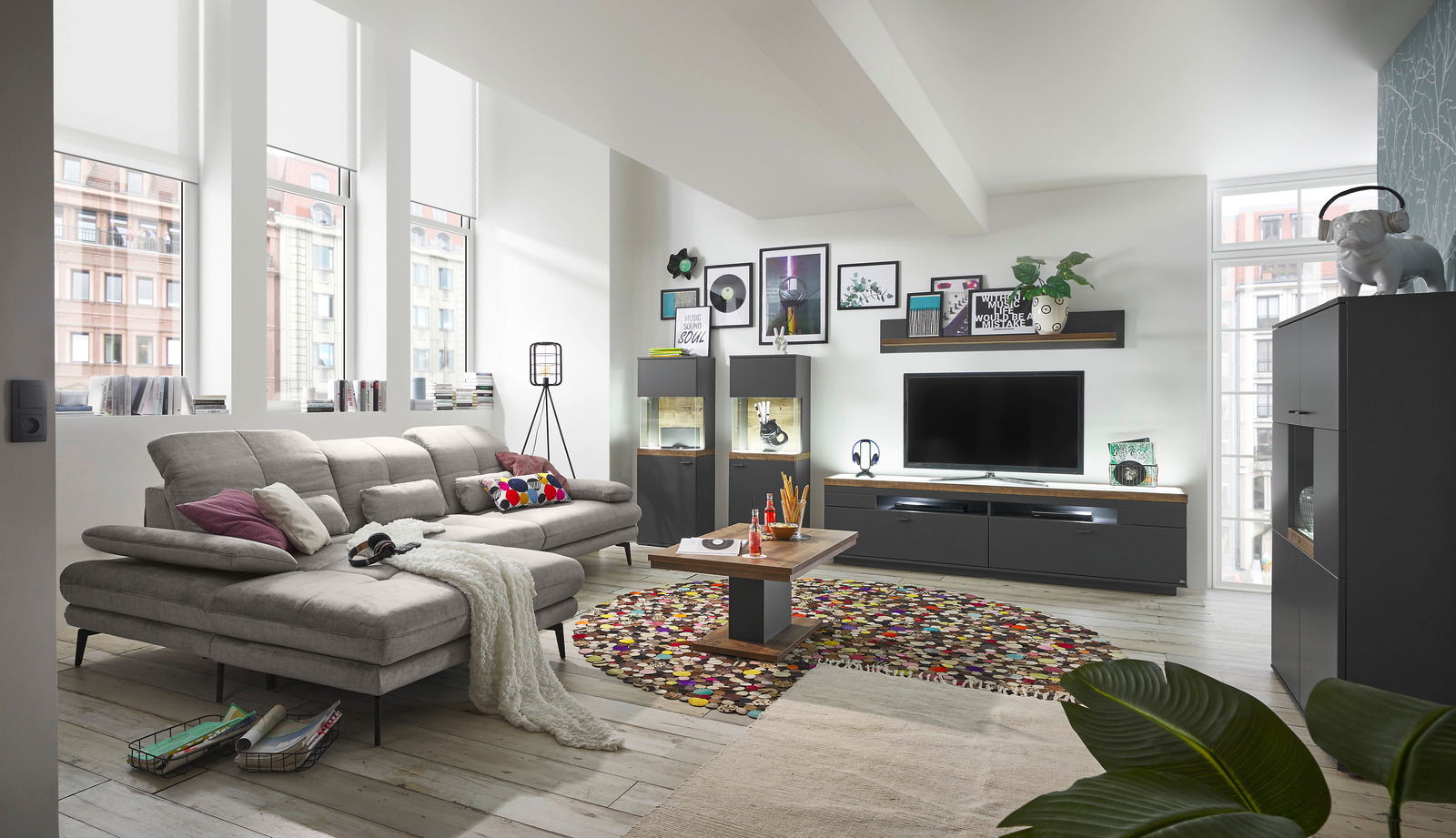 Modernes Wohnzimmer mit grauem Sofa, Couchtisch und TV-Lowboard in einer hellen, stilvollen Umgebung. Perspektive von der Seite.