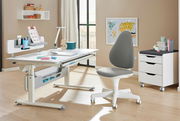 Moderner Jugenddrehstuhl in Grau und Weiß, seitliche Perspektive, neben einem höhenverstellbaren Schreibtisch in einem hellen Raum.