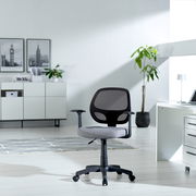 Moderner Drehstuhl mit Netzrückenlehne und grauem Sitzpolster, seitliche Perspektive in einem hellen Büro mit Pflanzen und Schreibtisch.