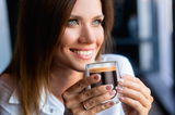 Frau hält ein doppelwandiges Thermoglas mit Espresso in der Hand, Nahaufnahme