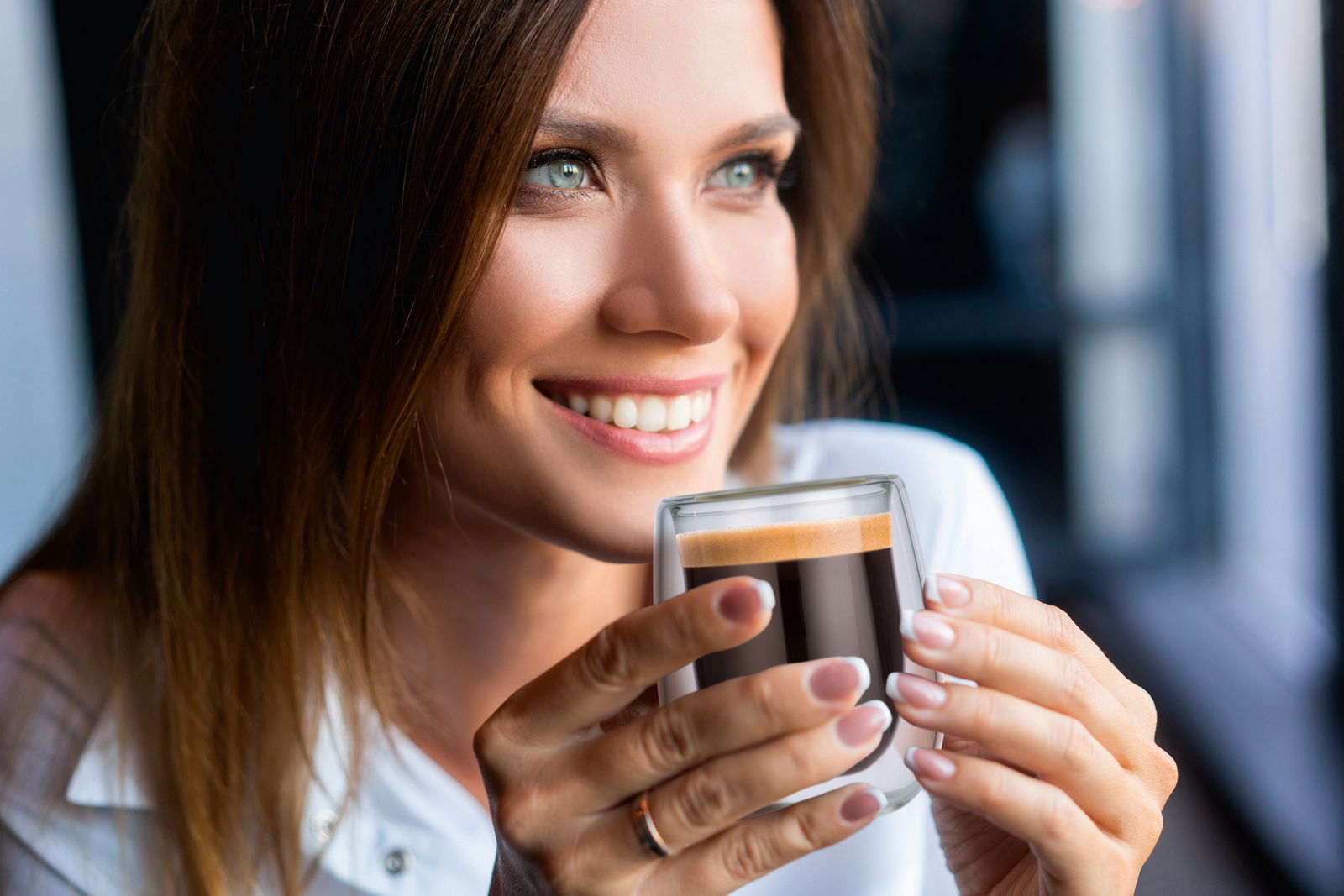 Frau hält ein doppelwandiges Thermoglas mit Espresso in der Hand, Nahaufnahme