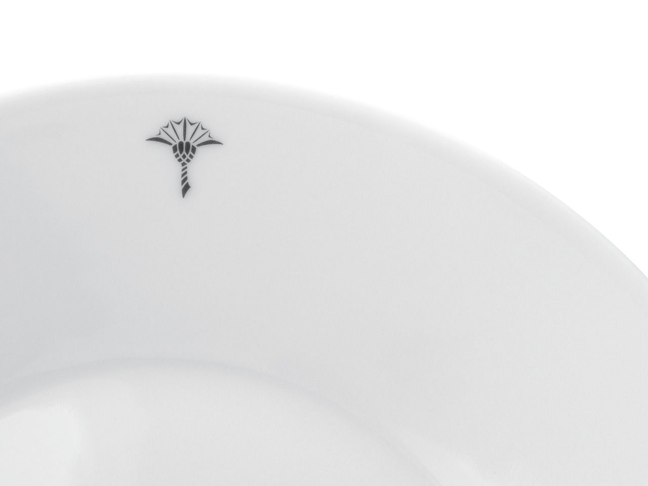 Nahaufnahme eines weißen Frühstückstellers mit einem dezenten schwarzen Emblem am Rand, von oben betrachtet.