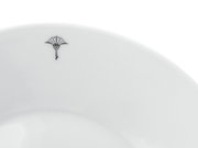 Nahaufnahme eines weißen Frühstückstellers mit einem dezenten schwarzen Emblem am Rand, von oben betrachtet.