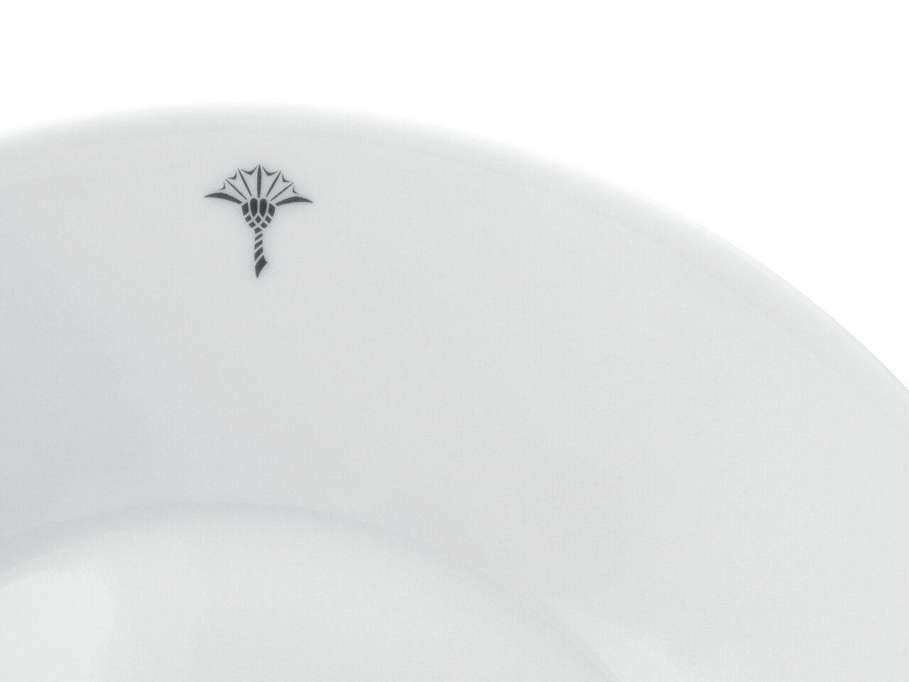 Nahaufnahme eines weißen Frühstückstellers mit einem dezenten schwarzen Emblem am Rand, von oben betrachtet.