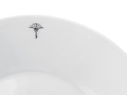 Nahaufnahme eines weißen Frühstückstellers mit einem dezenten schwarzen Emblem am Rand, von oben betrachtet.