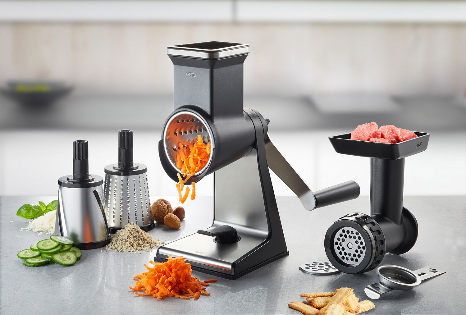 Set bestehend aus Trommelreibe und Fleischwolf, seitliche Perspektive, mit geriebenen Karotten und Fleischstücken.